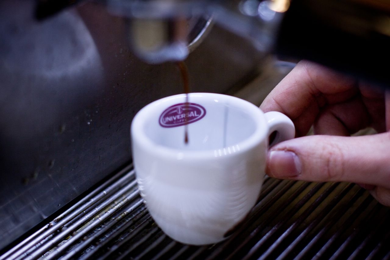 Home A detailed shot of espresso being poured into a white cup from a coffee machine.