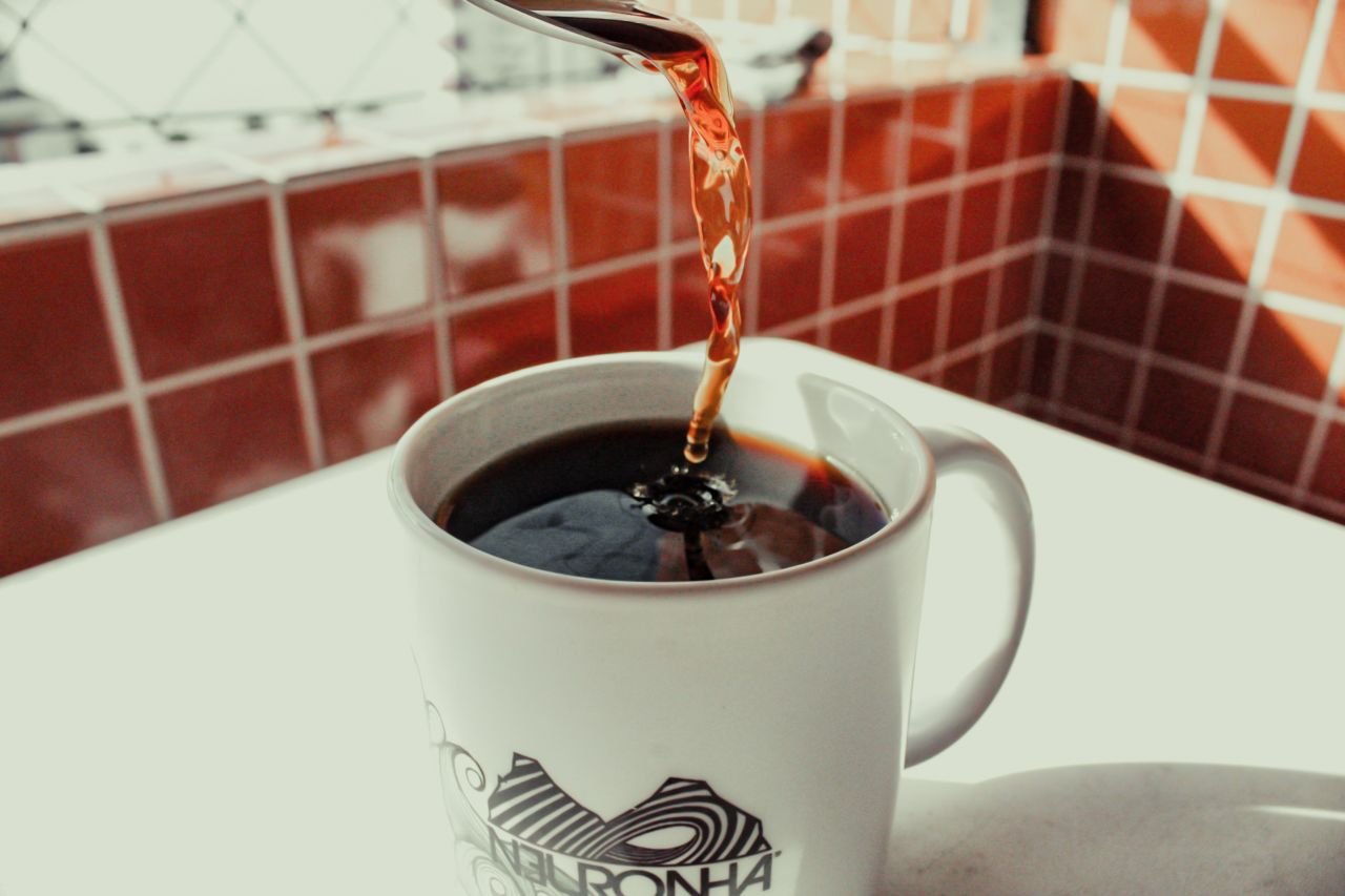 Home Close-up of freshly brewed coffee being poured into a stylish white mug on a tiled surface.