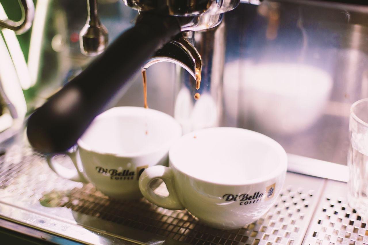 Crafting Captivating Headlines: Your awesome post title goes here Espresso machine brewing coffee into Di Bella cups in a café setting.